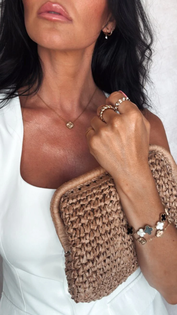 Woman holding a woven clutch with close-up of hand and jewelry